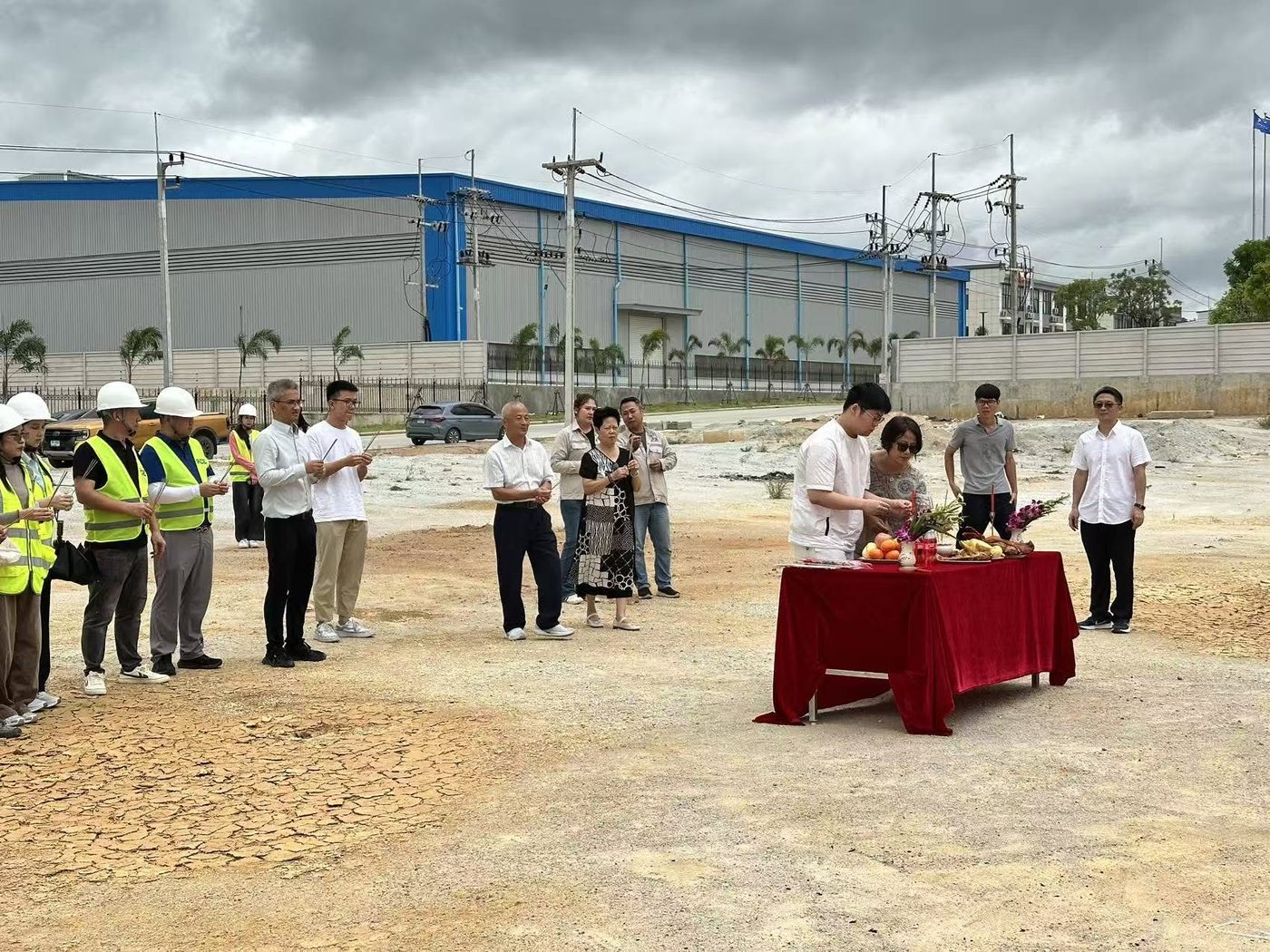 ผู้ร่วมงานถือธูปในช่วงพิธีบวงสรวงบนพื้นที่ก่อสร้าง